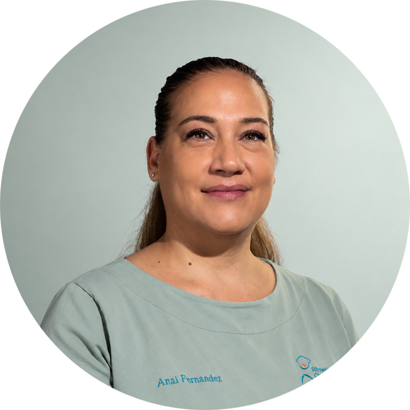 Anaí Fernández, profesional de Almería Quiropráctica, con uniforme verde claro y expresión amable, sobre un fondo verde suave